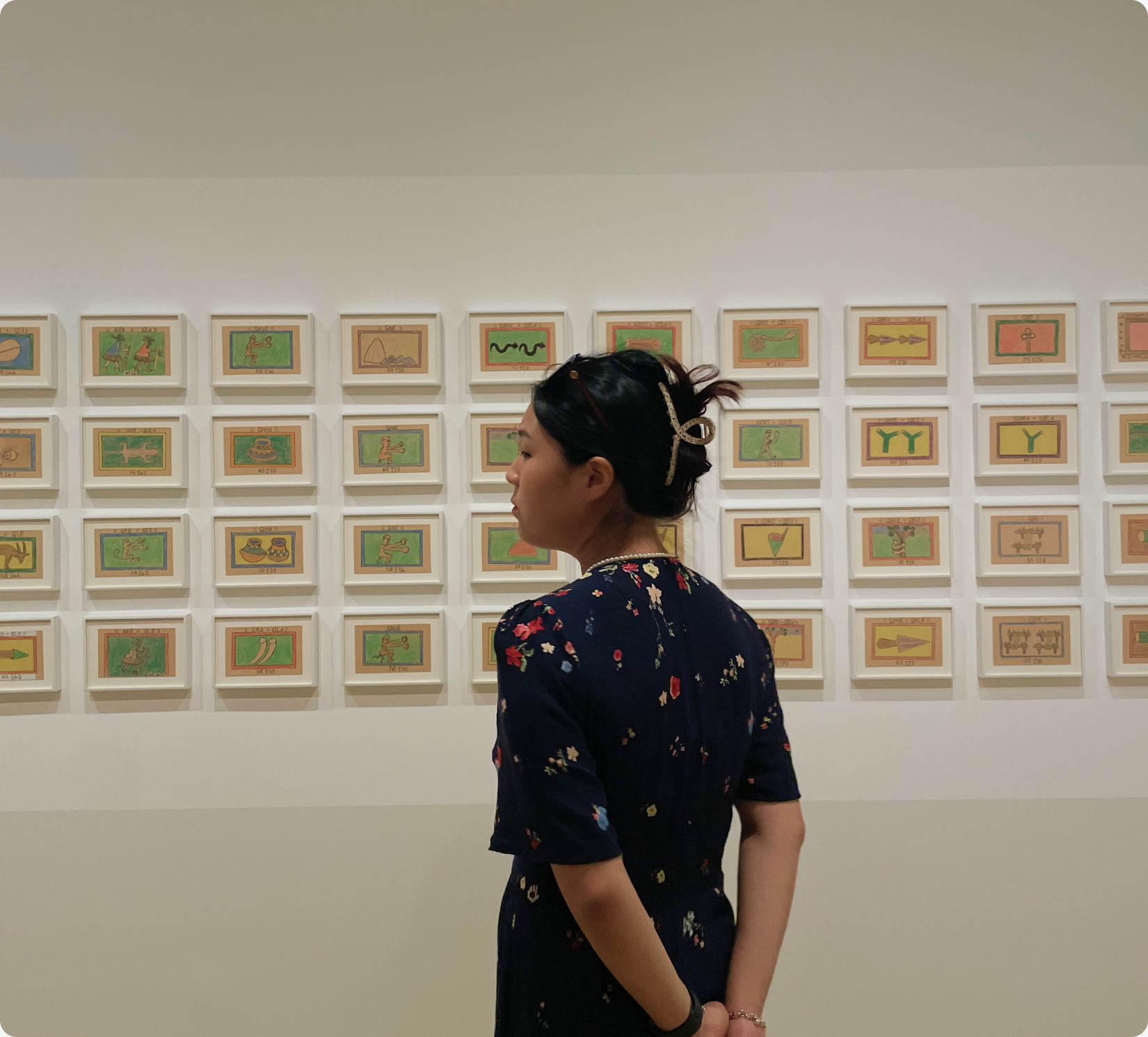 Younni exploring an art exhibition with a wall of framed artworks