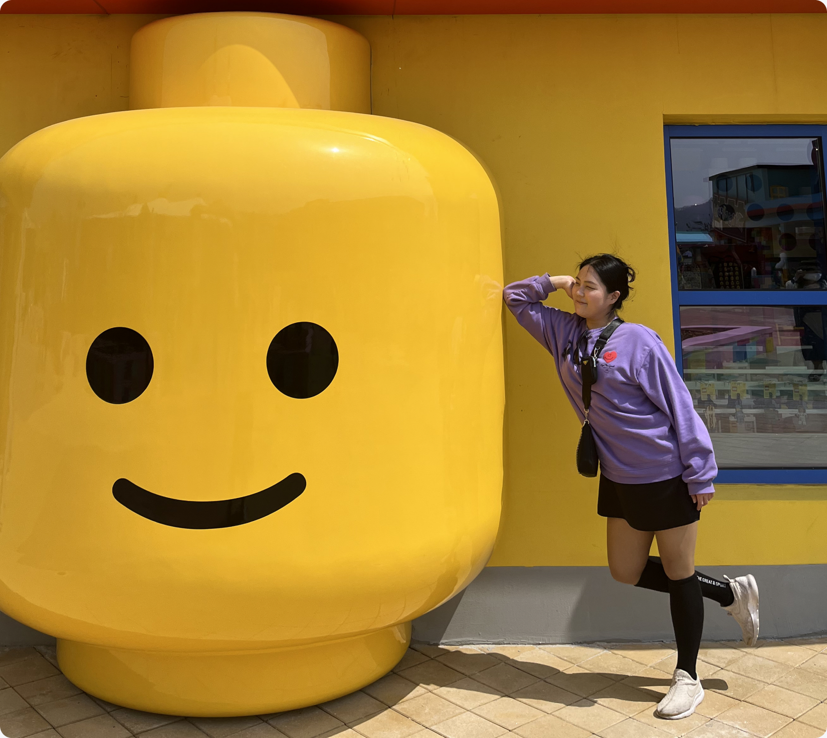 Younni beside a giant yellow LEGO figure at LEGOLAND